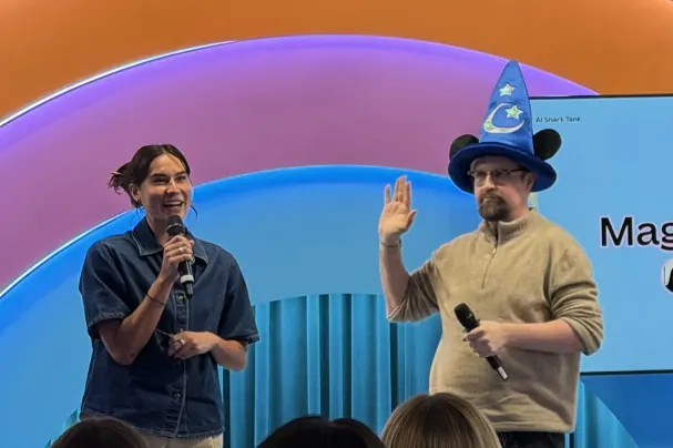 Shelby and Val standing onstage, with Val wearing a blue wizard hat
