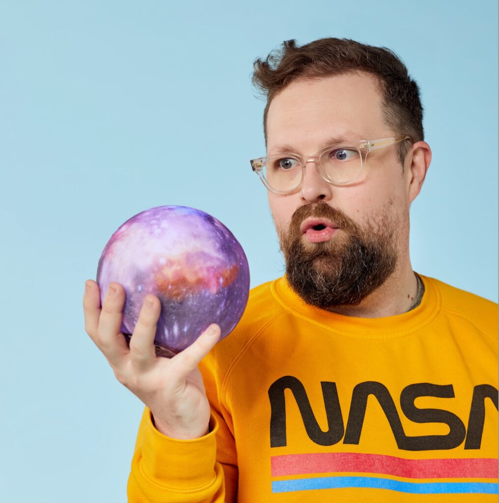 Close-up of me, Val Watkins, staring intently at a small plastic planet I am holding